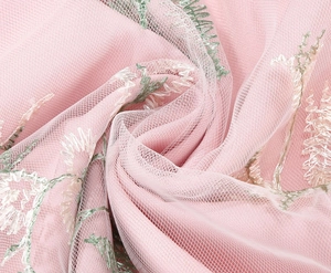 Close-up of delicate floral embroidery on light pink mesh fabric for elegant dresses