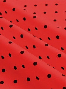 Gros plan sur le tissu à pois rouges soyeux montrant un drapé élégant et une matière lisse