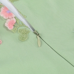Dettaglio di ricamo floreale e cerniera invisibile su abito verde chiaro