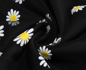 Detail of black mesh fabric featuring white daisy embroidery and floral patterns