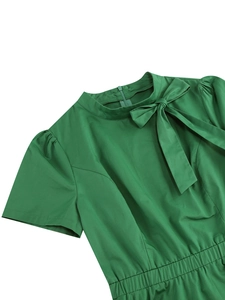 Dettaglio vestito verde scuro con collo alto, fiocco fisso e design con maniche a sbuffo