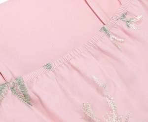 Detail of pink mesh fabric with silver-green floral embroidery and elastic pleated stitching