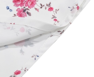 Detail of pink rose embroidery and delicate floral print on white vintage strap dress
