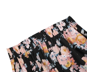 Detailed view of elastic waistband and colorful floral print on black midi skirt