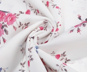 Close-up of white floral chiffon fabric with pink blossoms and elegant draped texture