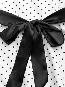 Détail macro d'une robe à pois avec un grand nœud en satin noir et une texture fine