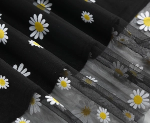 Detail of floral mesh tulle fabric showing white daisy embroidery on black layered skirt