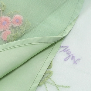 Dettaglio di abito in tulle verde chiaro con ricamo floreale e fodera in seta