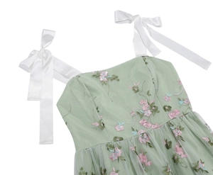 Detail of light green mesh dress with floral embroidery and white satin ribbon straps