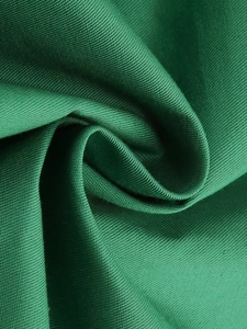 Dettaglio ravvicinato della trama del tessuto twill verde scuro e del drappeggio dell'abito