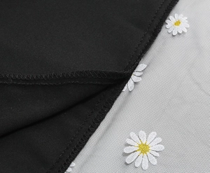 Detail of embroidered daisy pattern on sheer mesh fabric with premium sewing stitching