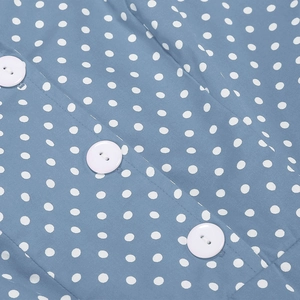 Détail du tissu bleu à pois de la robe montrant les boutons blancs et la texture
