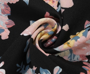 Macro shot of lightweight black floral fabric with pink and blue blossoms texture