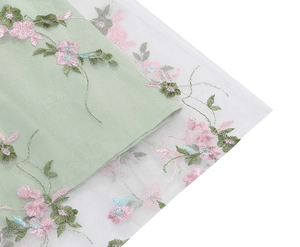 Detail of floral embroidery on pale green mesh fabric for an elegant sleeveless dress