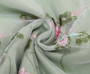 Close-up of elegant light green mesh fabric with detailed pink floral embroidery