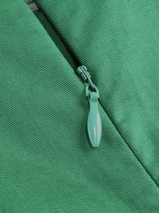 Dettaglio di un abito verde con cerniera a scomparsa e trama di tessuto a navetta fine