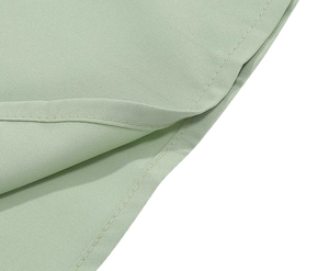 Detail of the mint green sleeveless dress showing fine stitching and woven fabric texture