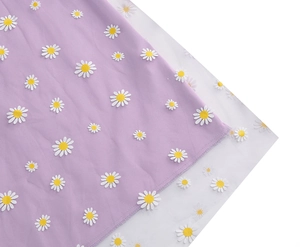 Detail of light purple fabric with white daisy embroidery and translucent mesh layering