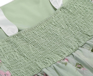 Detail of light green dress featuring floral embroidery on mesh and smocked bodice