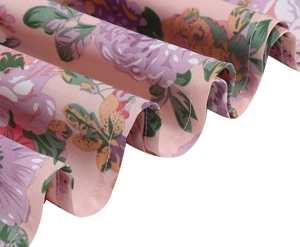 Macro view of light pink floral print fabric with purple and orange patterns and hem detail