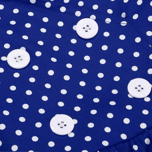 Detailed close-up of blue polka dot dress fabric featuring white decorative buttons