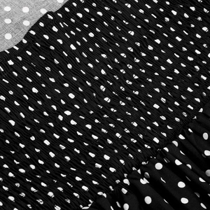 Close-up of vintage red polka dot fabric showing elastic smocking detail on the dress