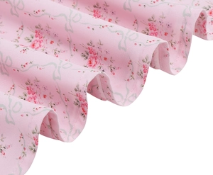 Close-up of pink floral dress fabric featuring delicate bow prints and ruffled edges
