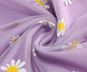 Close-up of purple mesh skirt fabric with white daisy prints and needlework texture