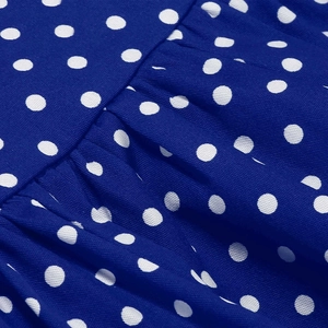 Detail of dark blue polka dot fabric showing fine texture and pleated dress design