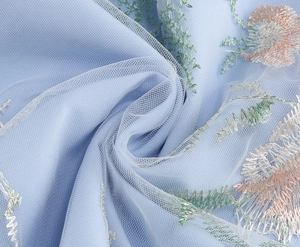 Detail of light blue mesh fabric with intricate floral embroidery and leaf patterns