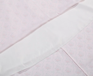 Detail of light pink rose and ribbon floral print fabric with neat lining seam work