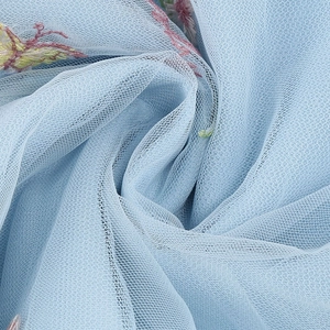 Dettaglio macro del tessuto in tulle blu con delicati ricami floreali e trama in pizzo