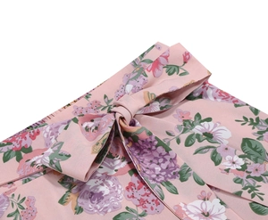 Detailed close-up of a pink floral midi skirt featuring a waist bow tie and twill fabric