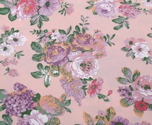 Close-up of floral print fabric with purple and white flowers on a soft pink base