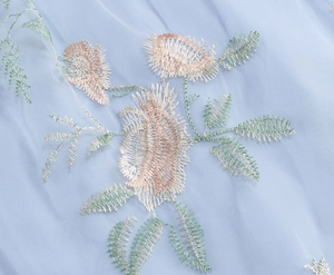 Close-up of floral embroidery on light blue mesh fabric for elegant vintage dress