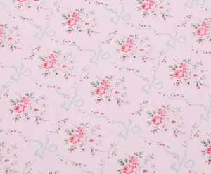 Detail shot of the vintage floral embroidery and green ribbon bows on pink dress fabric
