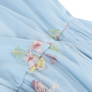 Dettaglio di ricamo floreale su tessuto in tulle azzurro di un abito in stile principessa