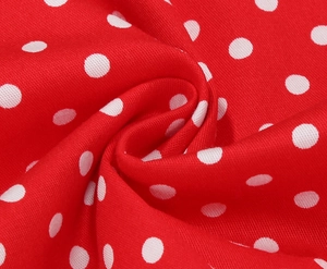 Gros plan sur le tissu rouge à pois blancs montrant la texture douce du matériau