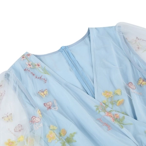 Dettaglio dello scollo a V e ricamo floreale colorato su abito in tulle blu