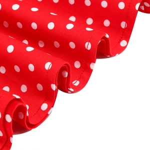 Detailed close-up of red and white polka dot fabric with elegant ruffled hem edges
