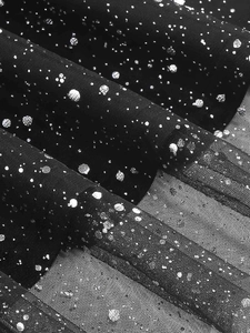 Close-up of black mesh fabric with silver sequins on elegant V-neck dress
