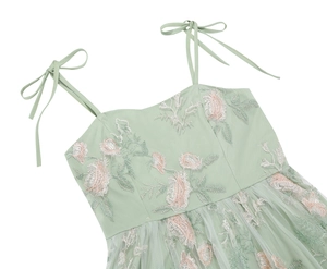 Detail of light green dress featuring floral embroidery and adjustable tie shoulder straps