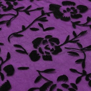 Macro detail of purple mesh fabric with black flocked floral texture and vintage patterns