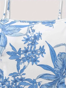 Détail du motif floral bleu sur une robe blanche avec de fines bretelles