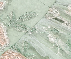 Detail of mint green mesh fabric with elegant leaf embroidery and delicate silver threads