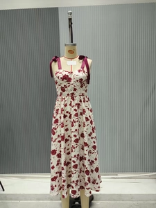 Détail d'une élégante robe blanche à fleurs avec des bretelles en ruban bordeaux