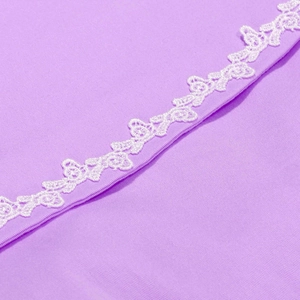 Détail de la dentelle papillon blanche sur le tissu violet d'une robe d'été