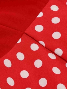 Detailed macro view of red fabric with white polka dots showing fine twill texture and seams