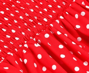 Detail of red polka dot cotton dress showing smocked elastic waist and pleated fabric