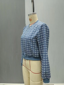 Detail of blue geometric plaid jacket featuring metal zipper and ribbed knit cuffs